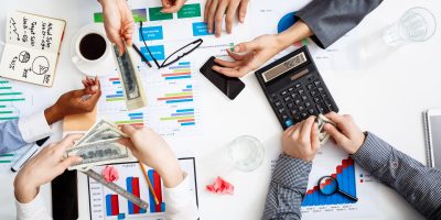 Picture of businessmen's hands on white table with documents, coffee and drafts